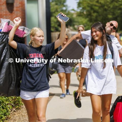 Stella Minge, left, let’s loose a yell as she and Lily Tobin, both of Omaha, head for their Schramm Hall room. Lily’s dad, B.J, photobombed the scene. Residence Hall move in for students participating in Greek Rush. August 14, 2022. Photo by Craig Chandler / University Communication.