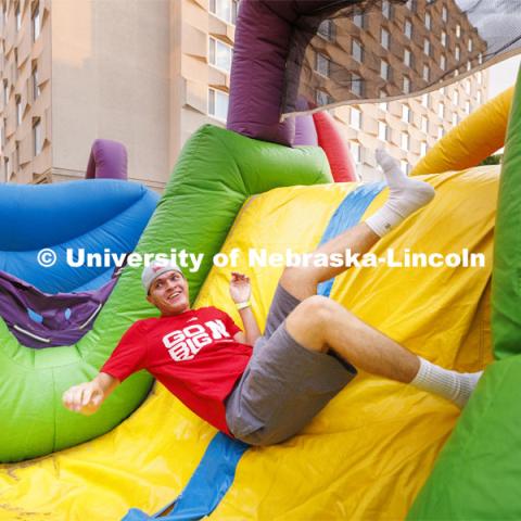 Derek Pirak, a freshman from South Dakota, tumbles through the inflatable obstacle course at the Harper Schramm Smith residence halls block party. August 18, 2022. Photo by Craig Chandler / University Communication.