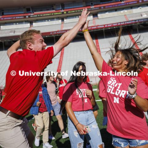 NSE Orientation Leader Jackson Anderson high fives Tatum Spray, a freshman from Phoenix, Arizona, as students form the “N” for the class photo in the stadium. Tunnel Walk and New Student Welcome in Memorial Stadium. August 19, 2022. Photo by Craig Chandler / University Communication.