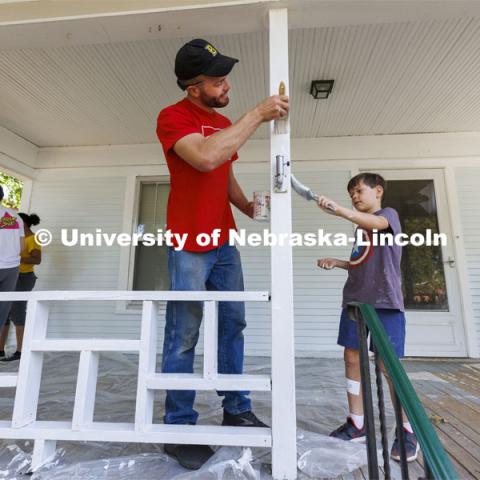 First-year law students Peter Liffrig from Bismarck North Dakota and Jude Weitzel, 8, son of new faculty member Paul Weitzel, team up to paint the porch trim. First-year law students, faculty, staff and family members come together to paint a house at 518 S. 26th Street. Photo by Craig Chandler / University Communication.