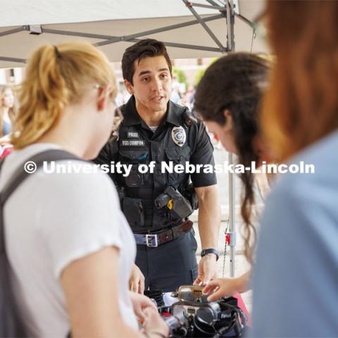 Officer Agustin Champion talks with students at the UNL Police Department booth before letting them try the goggles which simulate being under the influence. Sunday, the Street Fest filled the parking lot by East Stadium with hundreds of booths hosted by local businesses, nonprofit organizations, UNL departments and plenty of music, free food, giveaways and prizes. August 21, 2022. Photo by Craig Chandler / University Communication.
