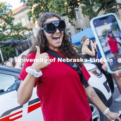 Grace Carey, a junior from Bellevue, Nebraska, has her photo taken by a friend as she wears goggles which simulate being under the influence. Sunday, the Street Fest filled the parking lot by East Stadium with hundreds of booths hosted by local businesses, nonprofit organizations, UNL departments and plenty of music, free food, giveaways and prizes. August 21, 2022. Photo by Craig Chandler / University Communication.