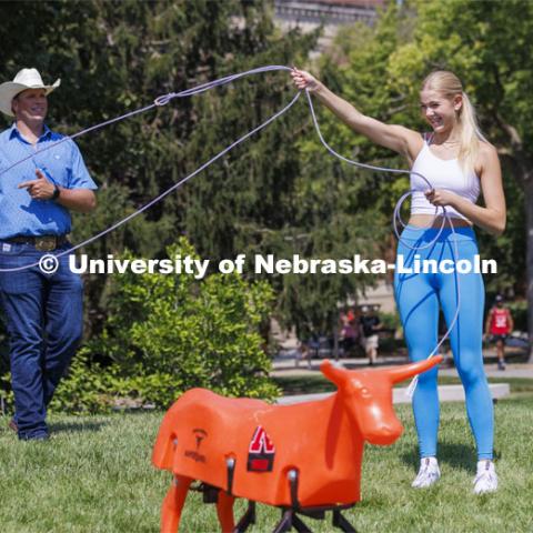 Gracie Jones, a freshman from Chadron, tries her hand at roping as Rodeo Club coach Marshal Peterson watches. Club Fair in the green space by the Nebraska Union at City Campus. More than 120 recognized student organizations (RSOs) to join for social, professional and leadership interests. RSO members and officers will be on hand to provide details about their organization and answer questions from prospective new members. August 24, 2022. Photo by Craig Chandler / University Communication.