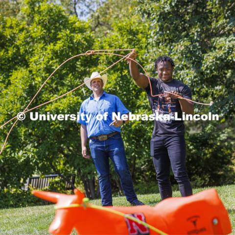 Jerran Henry, a sophomore, tries his hand at roping as Rodeo Club coach Marshal Peterson watches. Club Fair in the green space by the Nebraska Union at City Campus. More than 120 recognized student organizations (RSOs) to join for social, professional and leadership interests. RSO members and officers will be on hand to provide details about their organization and answer questions from prospective new members. August 24, 2022. Photo by Craig Chandler / University Communication.