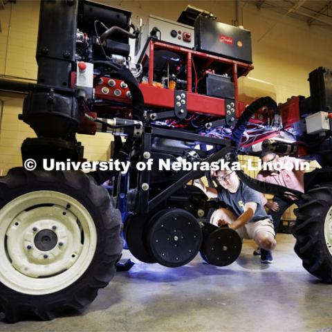 Santosh Pitla, right, watches as Chee Town Liew adjusts the height on the planter attachment of Pitla’s robotic tractor. The tractor is a testbed for automated agriculture and will be used to plant cover crop in the fall. September 2, 2022. Photo by Craig Chandler / University Communication.