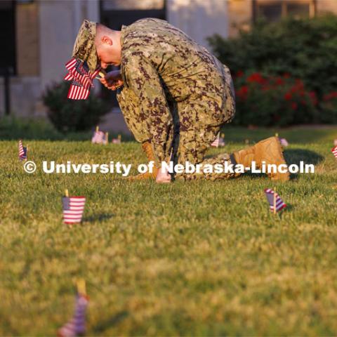 Navy Ensign Drew Merritt places a flag on the East Campus grass. Ens. Merritt is part of the navy ROTC cadre and is a Nebraska graduate. The Nebraska Military and Veteran Success Center, ASUN and others placed flags and signs on East Campus today to commemorate 9/11. The display will be moved to city campus on Monday. September 9, 2022. Photo by Craig Chandler / University Communication.