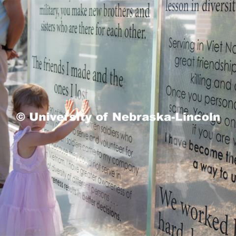 A young girl touches one of the glass panels of the new Veterans’ Tribute. Veteran's Memorial Ceremony. Dedication of Veterans’ Tribute project outside Military and Naval Science building. September 11, 2022. Photo by Gus Kathol for University Communication.