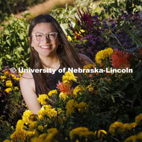 Isabella Villanueva smiles for a photo surrounded by flowers on East Campus. Villanueva is a sophomore fisheries and wildlife major and involved in MASA, CASNR Emerging Leaders in Diversity and MANRRS. She is working to coordinate a fundraiser to help plant native and pollinator plants in the community. September 20, 2022. Photo by Craig Chandler / University Communication.