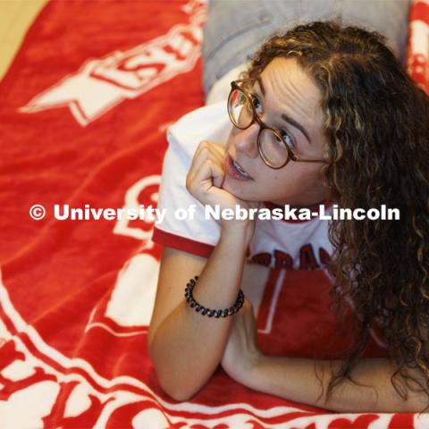 A student lays on the floor on her University of Nebraska blanket. Housing Photo Shoot in Able Sandoz Residence Hall. September 27, 2022. Photo by Craig Chandler / University Communication.