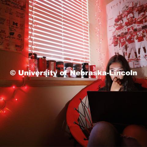 A student studies by the glow of red christmas lights in their University Suites Residence Hall room. Housing Photo Shoot in University Suites Residence Hall. September 27, 2022. Photo by Craig Chandler / University Communication.