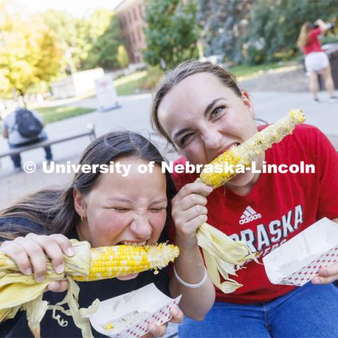 Malayna Wingert and Sophie Frappier dig into their ears of corn at Cornstalk. Homecoming Parade and Cornstalk. September 30, 2022. Photo by Craig Chandler / University Communication.