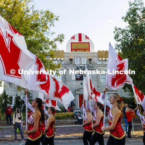 The Cornhusker Marching Band color guard has a super fan peeking out above the Alpha Tau Omega house. Homecoming Parade and Cornstalk. September 30, 2022. Photo by Craig Chandler / University Communication.