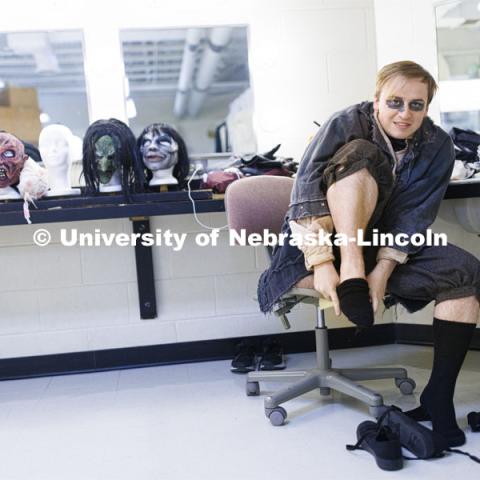 Jackson Wells puts on his socks and shoes as he costumes up to become The Gravedigger. ShakesFear production in the Temple Building. October 21, 2022. Photo by Craig Chandler / University Communication.