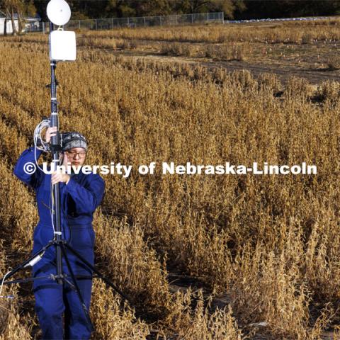 Graduate students Sang Won Shin carries a millimeter-wave (mmWave) radio with phased-array antenna out of a soybean field on east campus field. October 28, 2022. Photo by Craig Chandler / University Communication.
