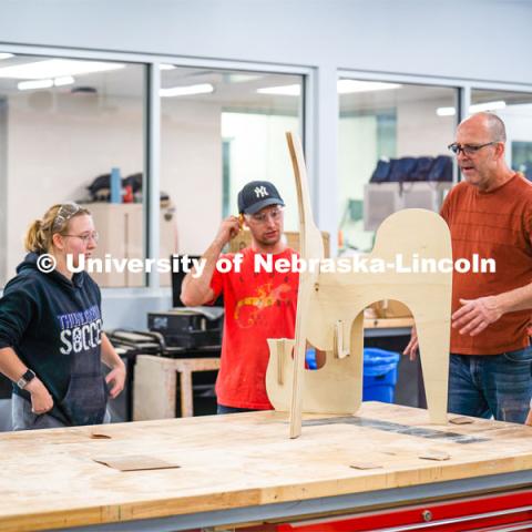 Aziza Cyamani, assistant professor of product design (left), students Elizabeth Loftus, Thomas Gerees, Chris Martin, professor emeritus at Iowa State University, and Caroline Gomel checks their nearly finished product. Architecture design professor Aziza Cyamani is doing a weekend long furniture design-build sprint with Professor Chris Martin from Iowa State University. The students will come Friday, Saturday and Sunday and make something out of wood and another version using a new technology like 3D printing. October 30, 2022. Photo by Kirk Rangel for University Communication.