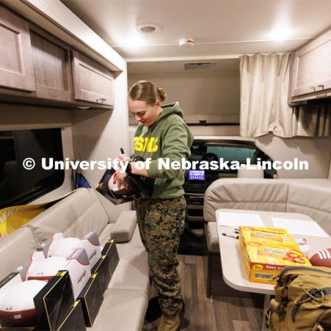 Jenalee Wimer, a junior in animal science and Marine Corp Reservist, signs donated footballs that are being signed by all the ruckers and carried along the route. Nebraska students and veterans march from Memorial Stadium Wednesday morning. "The Things They Carry" ruck march involving military and veteran students from Iowa and Nebraska. To raise awareness about veteran suicide, through the week, the students walk in 20-mile shifts carrying 20-pound backpacks to commemorate the estimated 20 veterans who die by suicide each day. November 15, 2022. Photo by Craig Chandler / University Communication.