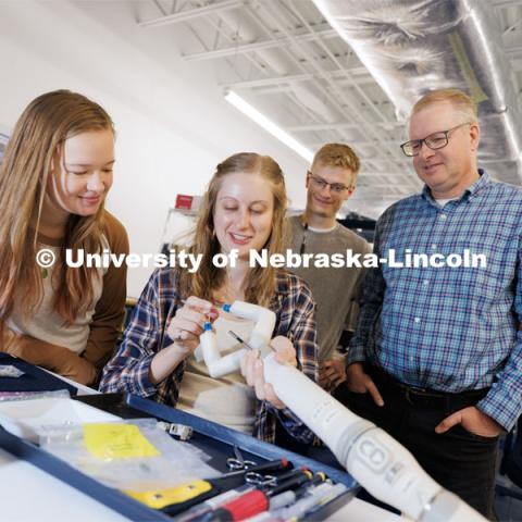 Rachael Wagner explains a robotic surgery device to undergrads Victoria Nelson, left, and David Ryan, center as Shane Farritor listens in. November 29, 2022. Photo by Craig Chandler / University Communication.