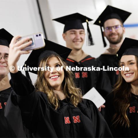 Morgan Erwin takes a selfie with fellow College of Business masters graduates. Graduate Commencement in Pinnacle Bank Arena. December 16, 2022. Photo by Craig Chandler / University Communication.