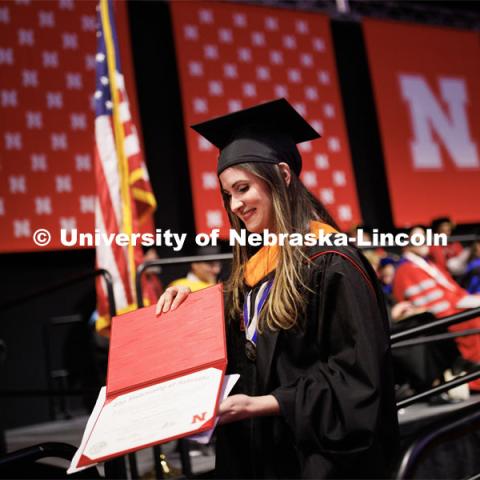 Tara Asgarpoor looks at her diploma as she walks off stage. Graduate Commencement in Pinnacle Bank Arena. December 16, 2022. Photo by Craig Chandler / University Communication.