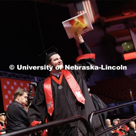 Jacob Muff, a graduate in Emerging Media Arts, waves to family and friends after receiving his diploma. Winter Undergraduate Commencement in Pinnacle Bank Arena. December 17, 2022. Photo by Craig Chandler / University Communication.