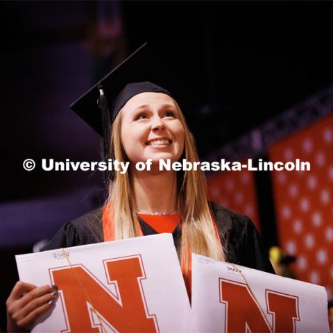 Allison Hinrichs holds her diplomas up for family and friends. Winter Undergraduate Commencement in Pinnacle Bank Arena. December 17, 2022. Photo by Craig Chandler / University Communication.