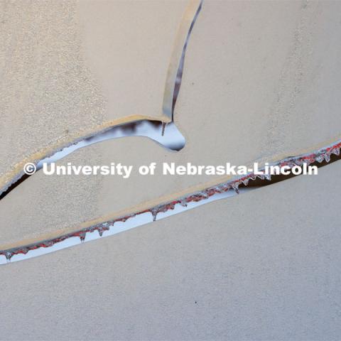 Icicles on the Torn Notebook glow red from the light of the Lied marquee. Ice and snow cover campus. January 19, 2023. Photo by Craig Chandler / University Communication.