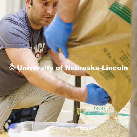 Andrew Brown helps pour the last of a large sack of oatmeal into a container for the volunteers to use. As part of MLK Week events, volunteers assembled hunger kits filled with oatmeal. The goal was more than 2,000 kits. January 25, 2023. Photo by Craig Chandler / University Communication.