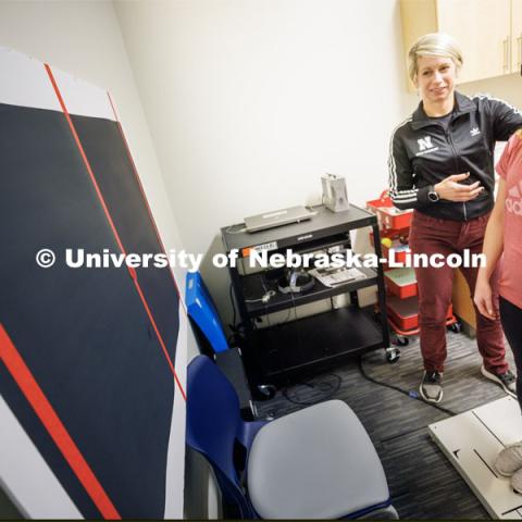 Dr. Kate Higgins, an Athletic Neuropsychologist with Husker Athletics, performs a mCOBALT test (a concussion balance test) on mock patient Makayla Burchett, a freshman from Harlan, Iowa. Burchett wears a laser pointer as she moves her head around a target on the wall while balanced on a force plate. The University Health Center and Nebraska Medicine recently moved its concussion clinic to the Nebraska Performance Lab in the east stadium space. February 1, 2023. Photo by Craig Chandler / University Communication.