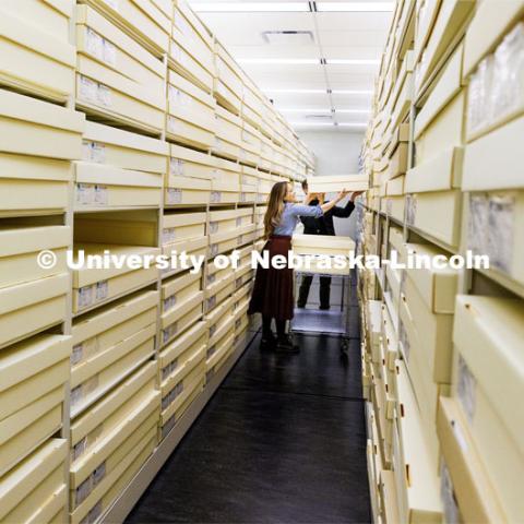 Sarah Walcott, collections manager, and Jamie Swartz, collections assistant, lift a quilt onto a storage rack in the center. Quilts that can be safely folded are stored in the boxes. Quilt Center. February 8, 2023. Photo by Craig Chandler / University Communication.