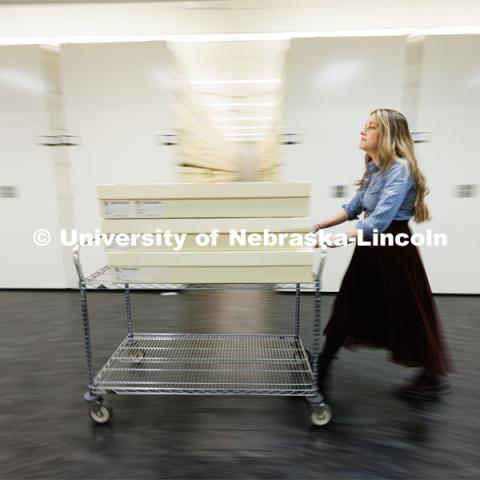 Sarah Walcott, collections manager, rolls a cart of quilts through the storage area. Quilts that can be safely folded are stored in the boxes. Quilt Center. February 8, 2023. Photo by Craig Chandler / University Communication.