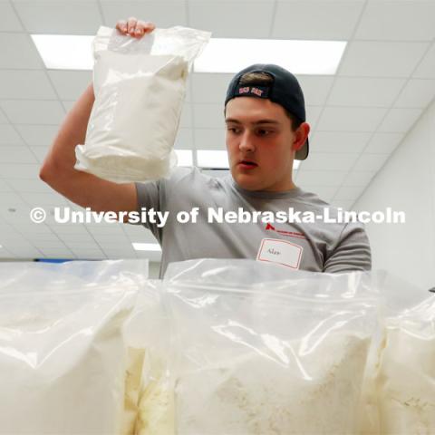 Adam Lierz grabs a package of flour from the ingredient selections during the Battle of the Food Scientists. Groups prepared baked goods using flour made from crickets. Battle of the Food Scientists at Nebraska Innovation Campus. February 15, 2023. Photo by Blaney Dreifurst / University Communication.