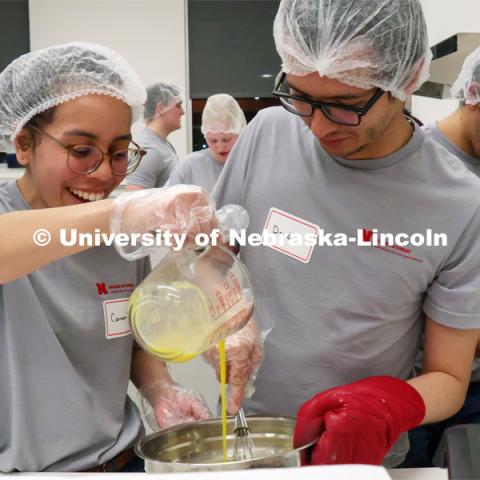 Carmen Perez-Donado pours egg into a mixture as David Fabian Gomez Quintero stirs during the Battle of the Food Scientists. Groups prepared baked goods using flour made from crickets. Battle of the Food Scientists at Nebraska Innovation Campus. February 15, 2023. Photo by Blaney Dreifurst / University Communication.