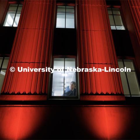 Jenna Baum, a junior in psychology, takes a break from studying in Love Library to look out at the lighted building. Glow Big Red. February 15, 2023. Photo by Craig Chandler / University Communication.