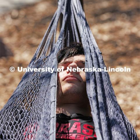 Ben Swidler, a sophomore from Buffalo Grove, Illinois, relaxes in the hammocks outside the Nebraska Union. Spring on City Campus. April 10, 2023. Photo by Craig Chandler / University Communication.