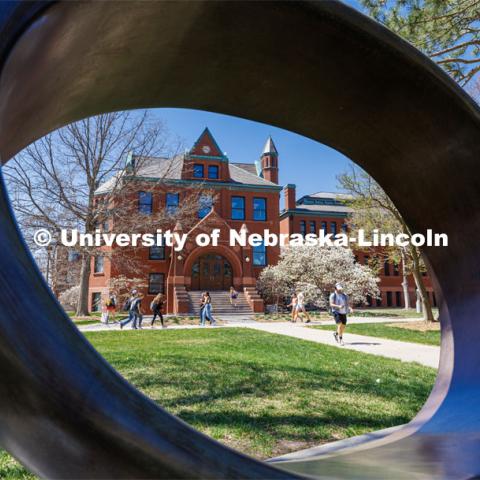 Architecture Hall is seen through the Fragment X-O sculpture in the Sheldon Sculpture Garden. City Campus. April 13, 2023. Photo by Craig Chandler / University Communication.