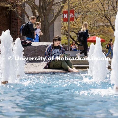 Erin Dodds, a junior from Oak Hills, California, dips her toes in the Broyhill Fountain while studying outside the Nebraska Union. Spring on City Campus. April 18, 2023. Photo by Craig Chandler / University Communication.