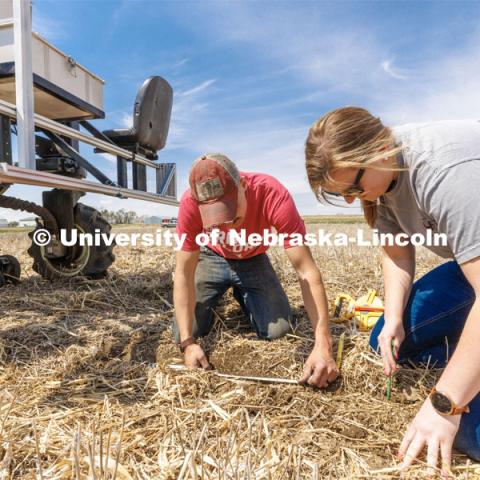 Graduate student Ian Tempelmeyer, left, and graduate research assistant Taylor Cross dig through the dirt to check for seed planting depth and spacing. The self-driving robotic planter based on Santosh Pitla’s tractor platform works its way through a field at the Rogers Memorial Farm east of Lincoln. April 27, 2023. Photo by Craig Chandler / University Communication.