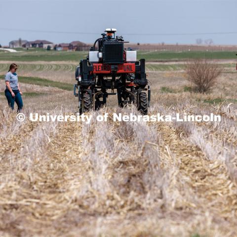 Graduate research assistant Taylor Cross (left) and graduate student Ian Tempelmeyer walk behind the Flex-Ro autonomous planting robot as it starts a row at Rogers Memorial Farm, east of Lincoln. Santosh Pitla, associate professor of advanced machinery systems at Nebraska, has managed the project since the robot’s inception in 2015. April 27, 2023. Photo by Craig Chandler / University Communication.