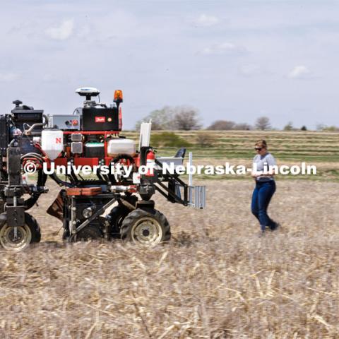 Graduate student Ian Tempelmeyer, right, and graduate research assistant Taylor Cross walk behind the Flex-Ro autonomous planting robot as it starts a row. The self-driving robotic planter based on Santosh Pitla’s tractor platform works its way through a field at the Rogers Memorial Farm east of Lincoln. April 27, 2023. Photo by Craig Chandler / University Communication.