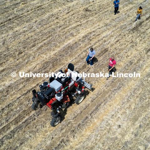 Graduate student Ian Tempelmeyer, red shirt, and graduate research assistant Taylor Cross walk behind the Flex-Ro autonomous planting robot as it starts a row along with others from the lab. The self-driving robotic planter based on Santosh Pitla’s tractor platform works its way through a field at the Rogers Memorial Farm east of Lincoln. April 27, 2023. Photo by Craig Chandler / University Communication.