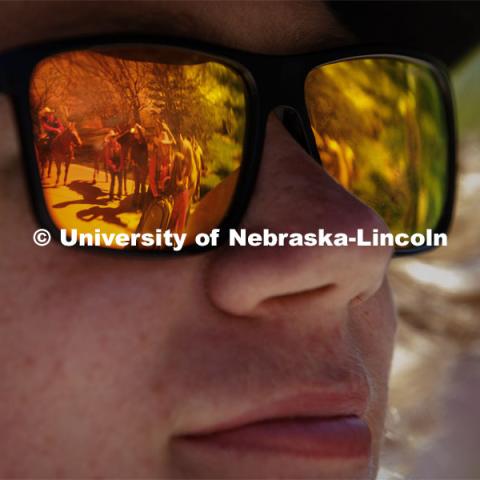 The rodeo event is reflected in the sunglasses of rodeo club member Gavin Guldner, a freshman from California. Students in Rob Simon’s capstone marketing course held a promotional event for the UNL rodeo on the west side of the Union on City Campus. The class developed a marketing strategy for the Rodeo Club to help promote their upcoming rodeo. Seven horses and multiple club members were on city campus for students to meet, get close to and have their photos taken. May 1, 2023. Photo by Craig Chandler / University Communication.