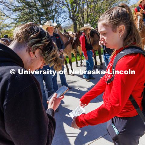 A student scans a QR code held by Reagan Montross, a senior in marketing, to obtain tickets for the weekend rodeo. Students in Rob Simon’s capstone marketing course held a promotional event for the UNL rodeo on the west side of the Union on City Campus. The class developed a marketing strategy for the Rodeo Club to help promote their upcoming rodeo. Seven horses and multiple club members were on city campus for students to meet, get close to and have their photos taken. May 1, 2023. Photo by Craig Chandler / University Communication.