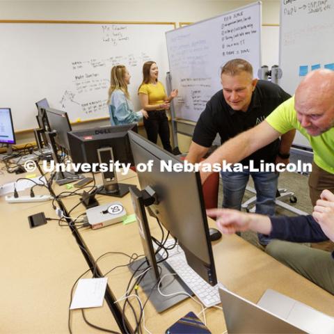 Erik Konnath, right, talks with members of the Allo team, Ed Jarrett and Jon McHenry (in yellow t-shirt) as they discuss the project. In the background from left are Design Studio team members Samuel Rangira, Sophie Hellebusch, Sophie Hill and Hannah Pokharel. May 2, 2023. Photo by Craig Chandler / University Communication.