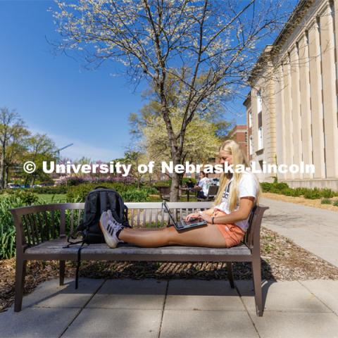 Izzy Knutson, a sophomore from Lincoln, sits outside Love Library working on her laptop. May 4, 2023. Photo by Craig Chandler / University Communication.