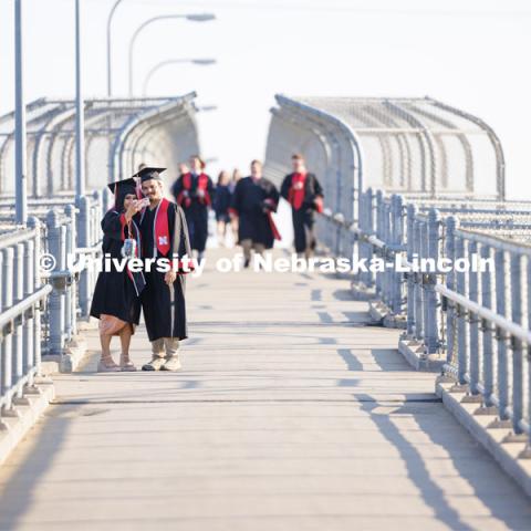 Stephanie Perez and Bailey Mulling take a selfie on the pedestrian bridge by Memorial Stadium as they walk to commencement. Undergraduate commencement at Memorial Stadium. May 20, 2023. Photo by Craig Chandler / University Communication.