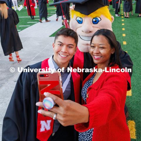 Husker Cheer Squad member Logan Larsen, cheer coach Erynn Butzke and Herbie Husker pose for a selfie before the ceremony. Undergraduate commencement at Memorial Stadium. May 20, 2023. Photo by Craig Chandler / University Communication.