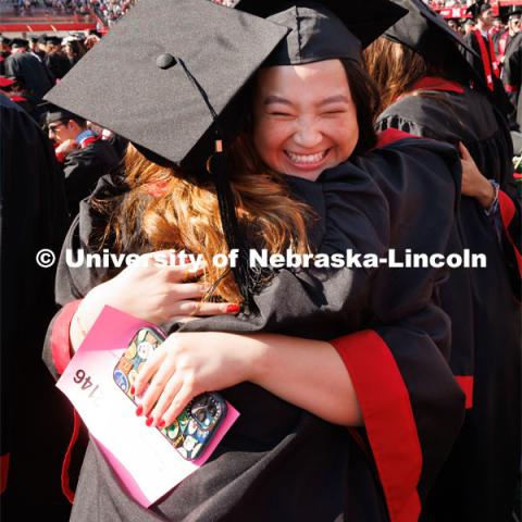 Olivia Kinne hugs Madilyn Jaskae as part of Regent Tim Claire’s request that the graduates acknowledge each other with a hug, fist bump or hello. Undergraduate commencement at Memorial Stadium. May 20, 2023. Photo by Craig Chandler / University Communication.