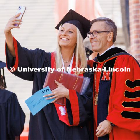 Taylor Peter, a Chancellor Scholar who finished at UNL with a 4.0 GPA, takes a selfie with Chancellor Ronnie Green after she received her diplomas. Undergraduate commencement at Memorial Stadium. May 20, 2023. Photo by Craig Chandler / University Communication.