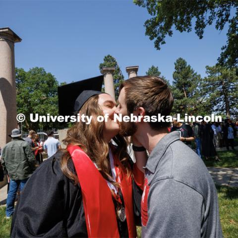 Kloee Sander gets a kiss from her fiancé, Joseph Placke near the kissing columns after commencement. Undergraduate commencement at Memorial Stadium. May 20, 2023. Photo by Craig Chandler / University Communication.