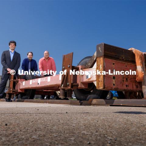 From left: Cody Stolle, Josh Steelman and Ron Faller lean against a sled connected to a ground anchor. The sled will be pulled to at a high speed to test the strength of the anchor for stopping it. Cody Stolle, Research Assistant Professor and Assistant Director of the Midwest Roadside Safety Facility is leading a group researching better checkpoint barriers to help the Department of Defense. June 5, 2023. Photo by Craig Chandler / University Communication.
